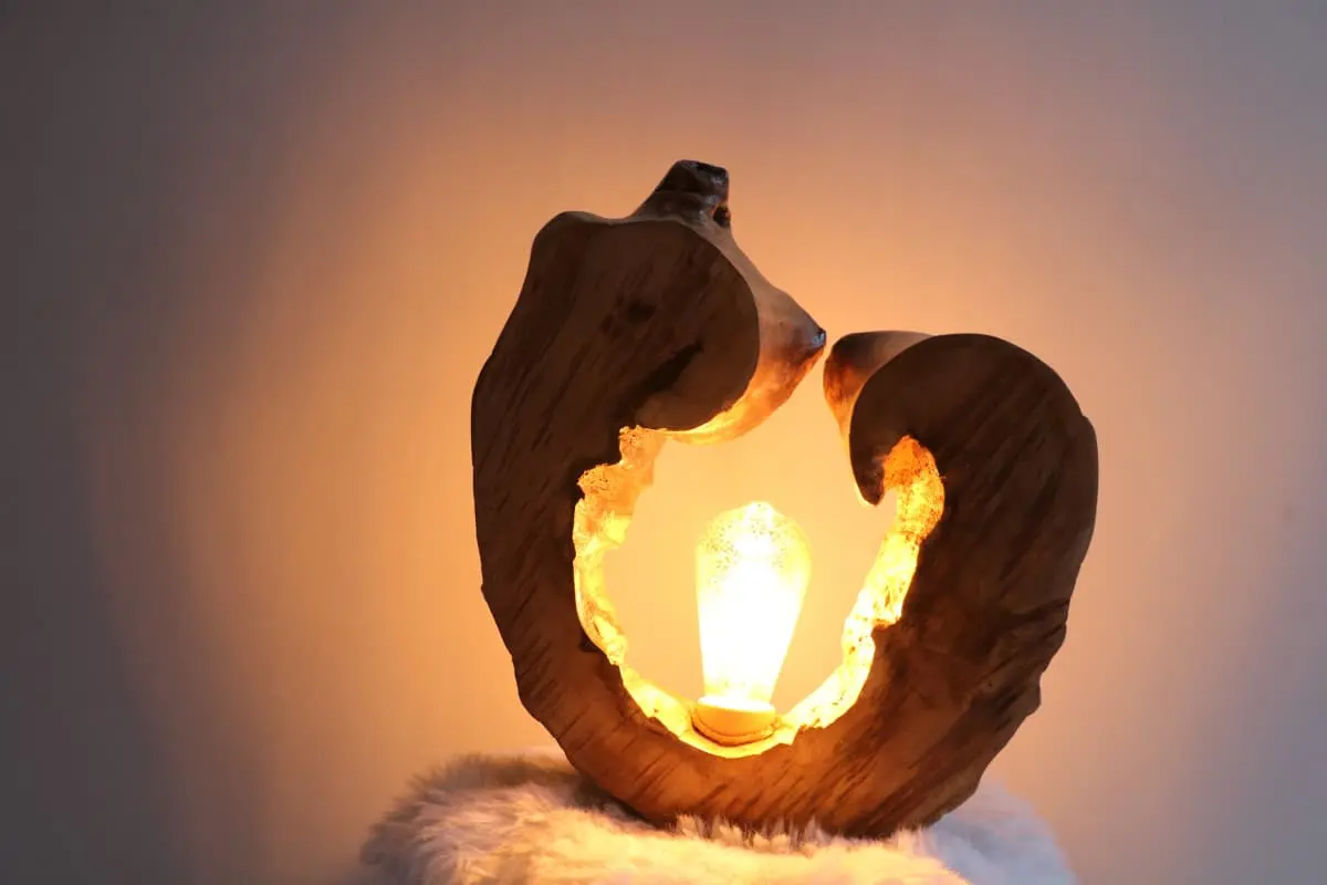 Lampe en bois sculpté avec ampoule allumée, ambiance chaleureuse et naturelle