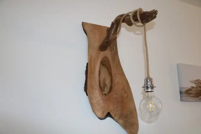 Lampe murale en bois naturel avec ampoule ronde suspendue par une corde, design rustique et artisanal