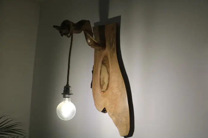 Lampe murale en bois naturel avec ampoule ronde suspendue par une corde, design rustique et artisanal