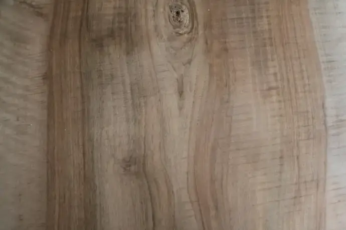 Gros plan sur une planche de bois naturel avec veines et nœuds visibles, texture rustique